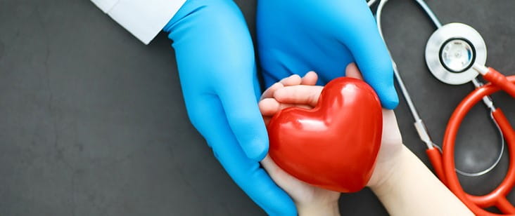 doctor holding patient hands with red heart and stethoscope 