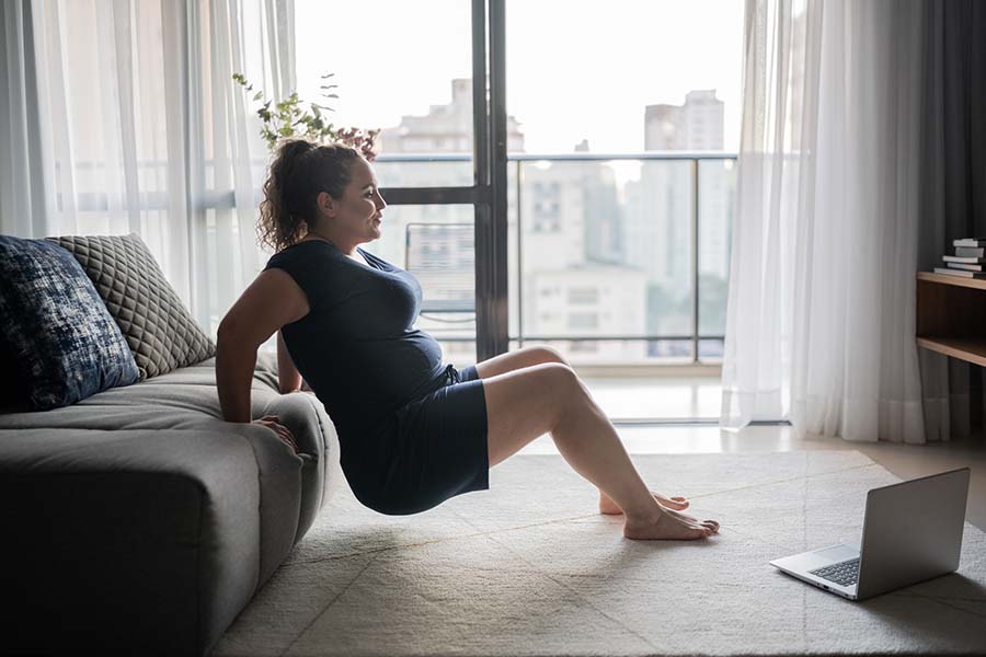 Woman exercising at home, leaning on couch