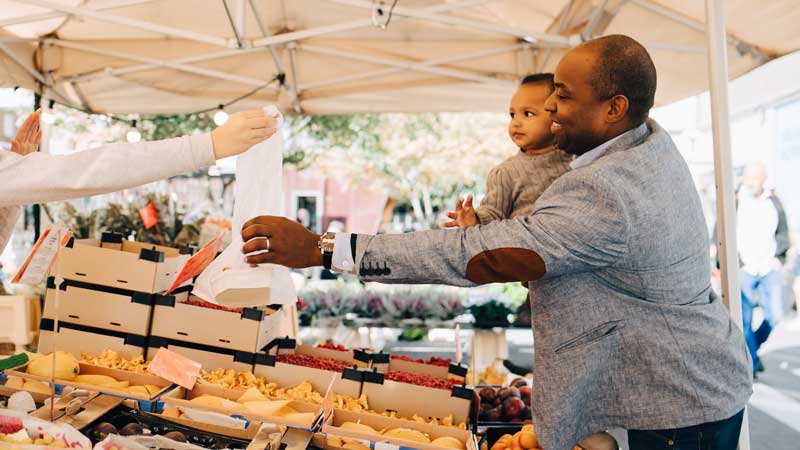 man and child buying veggies at farmers market