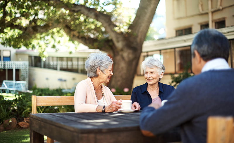 senior friends drinking coffee outdoors