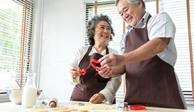 middle aged wife and husband having fun making valentine cookies